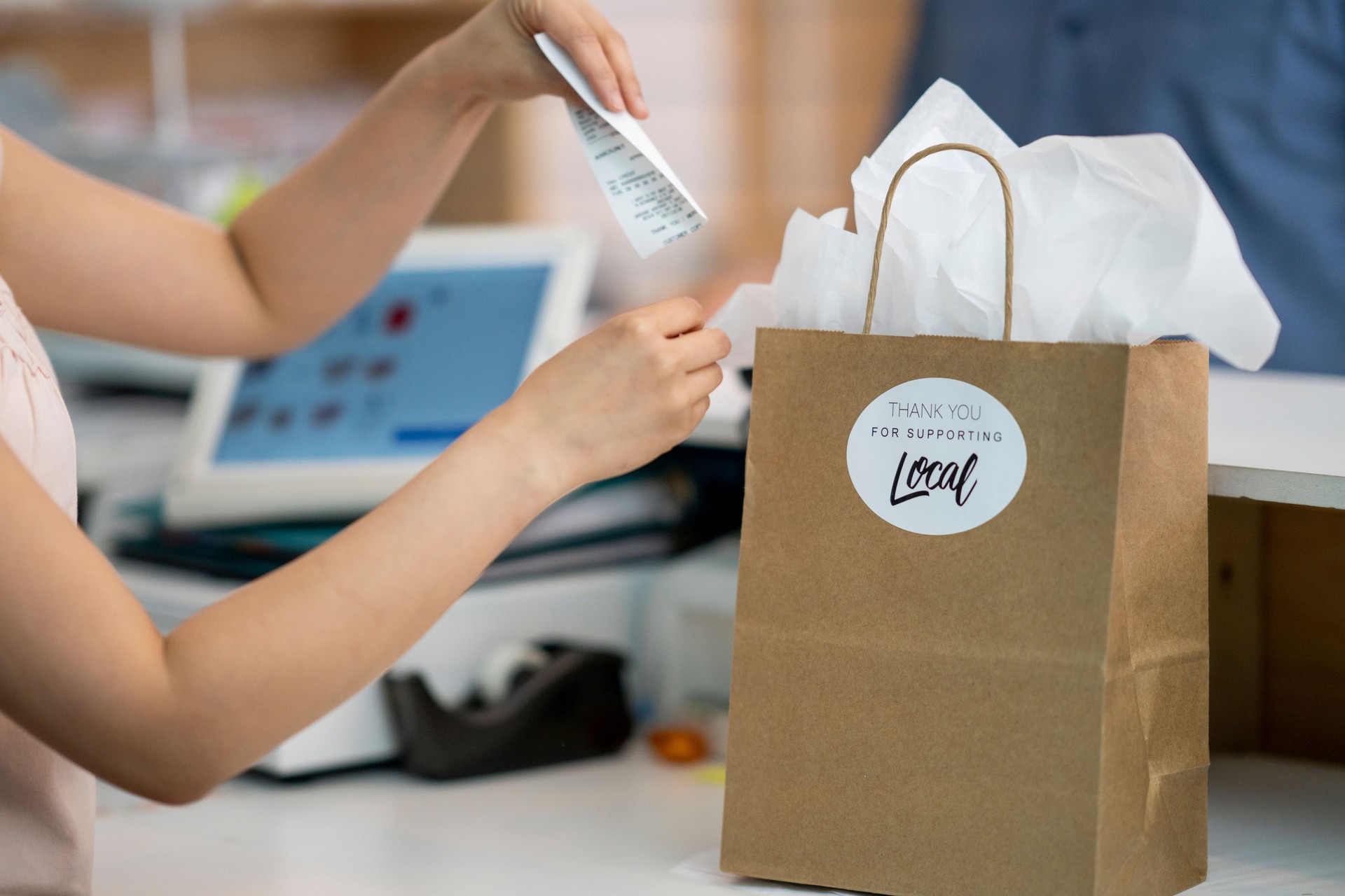 Shop owner placing receipt in shopping bag for customer